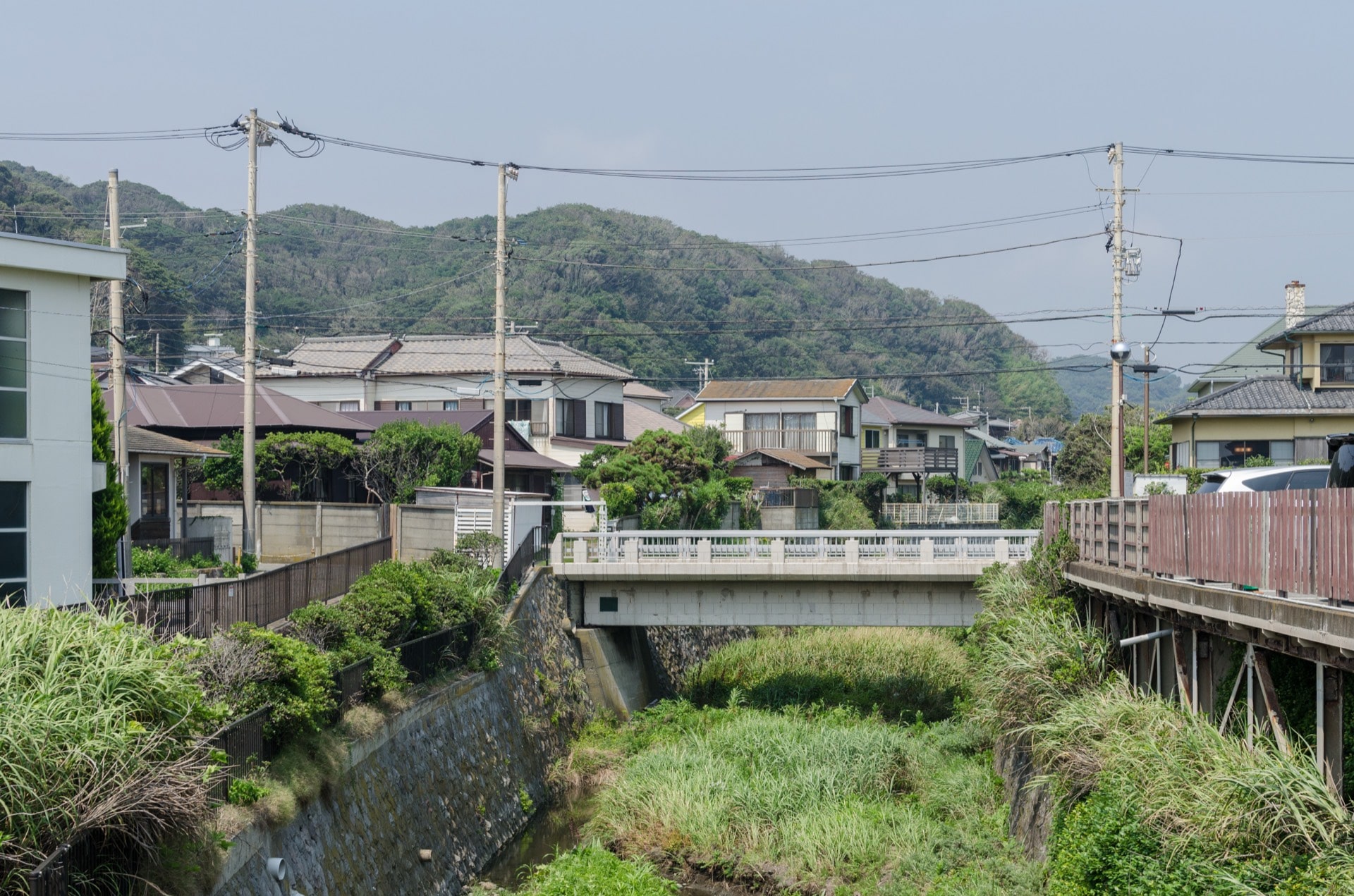 Detached houses by a small river below wooded hills in Inamuragasaki, Kamakura