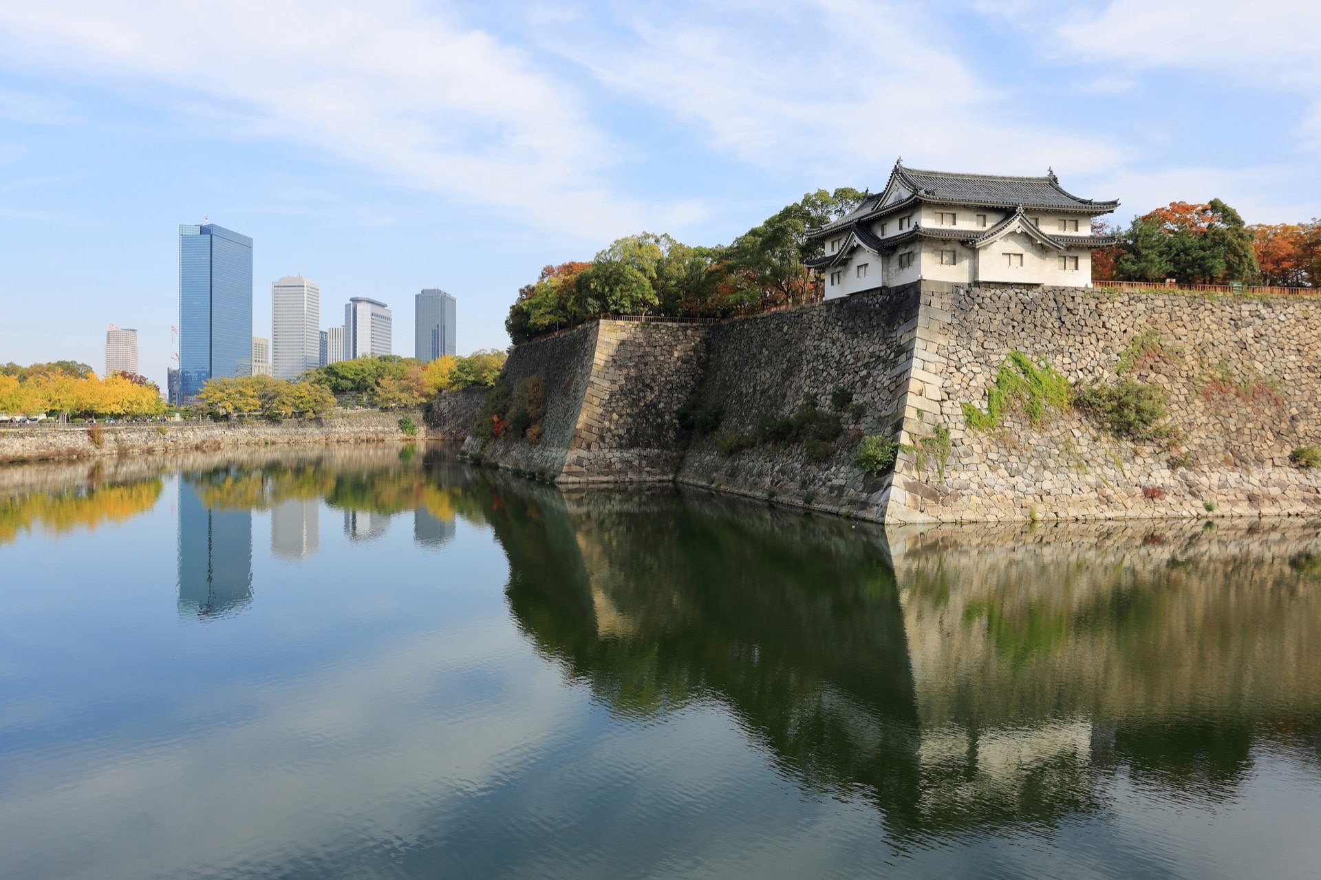 The outer moat and stone walls of Osaka Castle, with the towers of Osaka Business Park behind